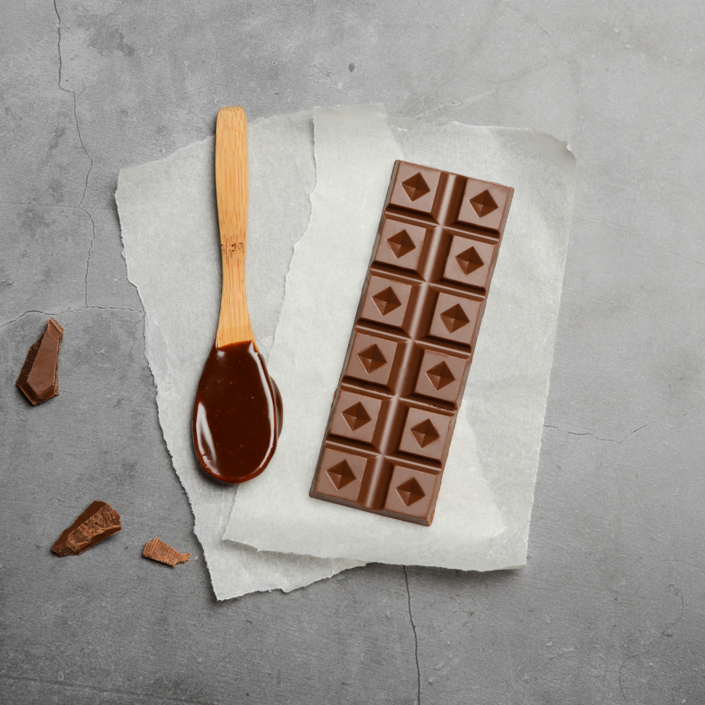 Tablette de chocolat au lait et cuillère de caramel, vue de dessus sur fond gris