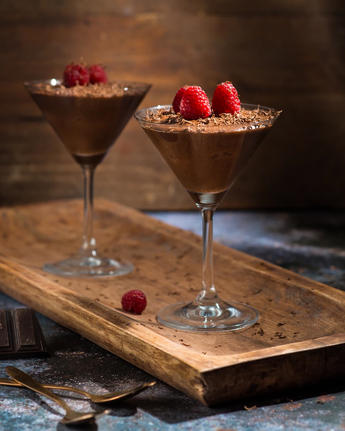 Deux verres de mousse au chocolat aux framboises sur un plateau en bois